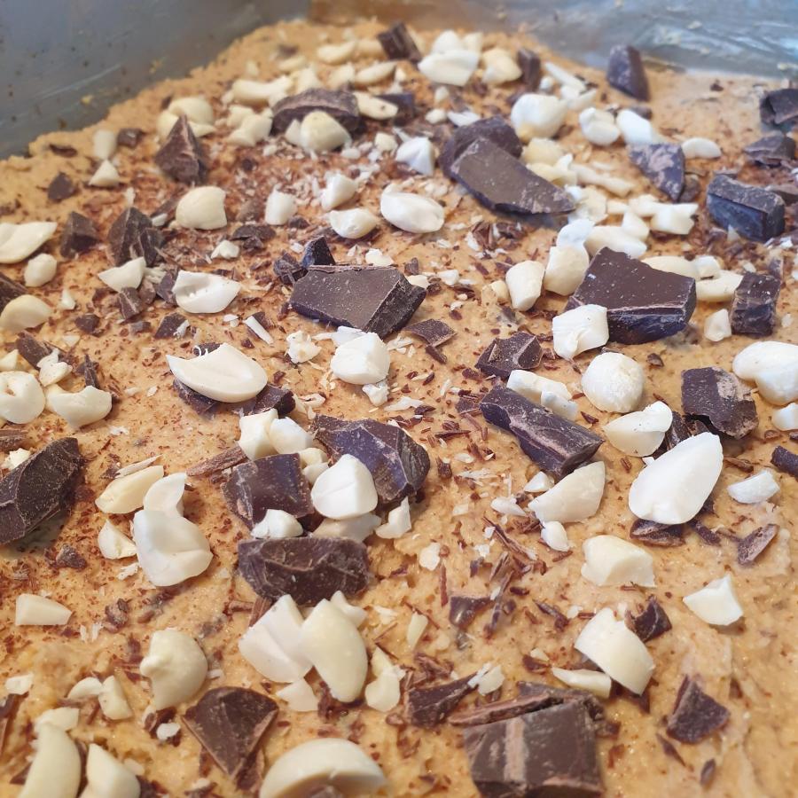 Chickpea blondie mixture with added nuts and chocolate on top to show what it looks like before it goes in the oven.
